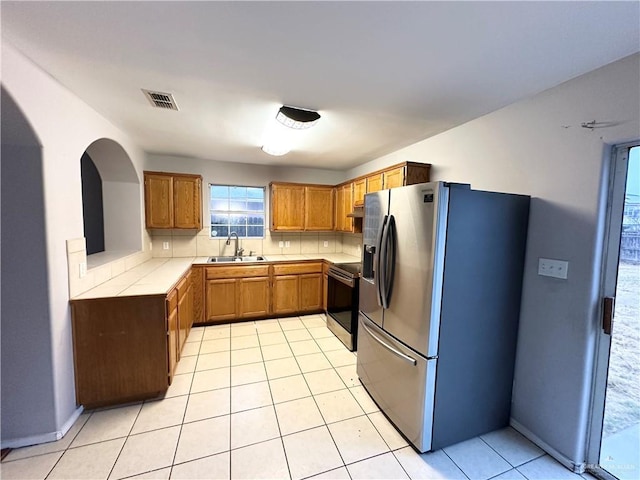 kitchen with visible vents, brown cabinetry, stainless steel appliances, light countertops, and a sink