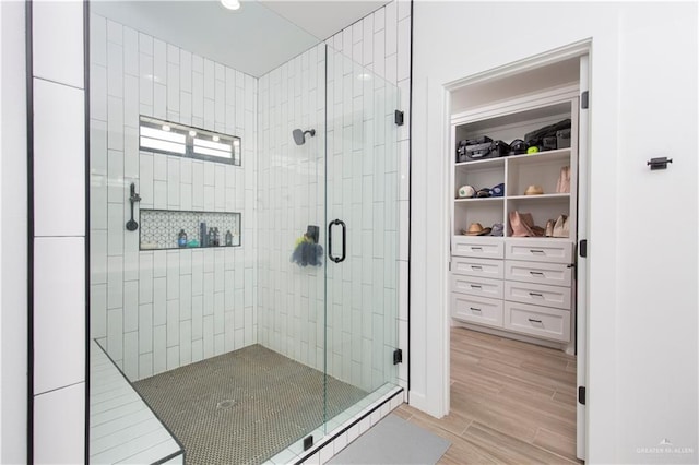 bathroom featuring a stall shower, a spacious closet, and wood finished floors