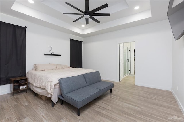 bedroom featuring light wood-style flooring, baseboards, a raised ceiling, and recessed lighting