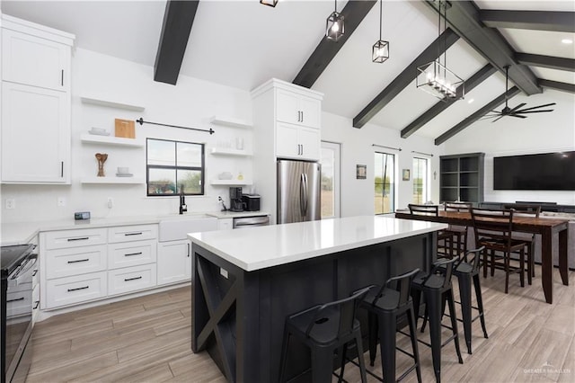 kitchen with a ceiling fan, stainless steel appliances, light countertops, open shelves, and a sink