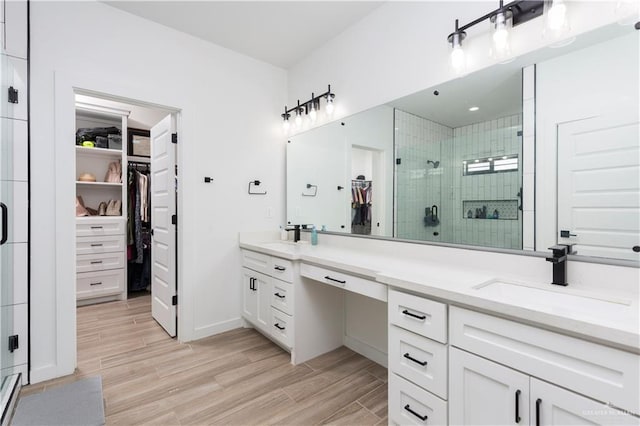 bathroom featuring a stall shower, double vanity, a sink, and wood tiled floor