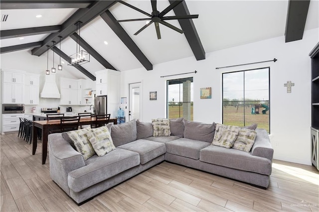 living room featuring ceiling fan with notable chandelier, high vaulted ceiling, beam ceiling, and light wood-style floors