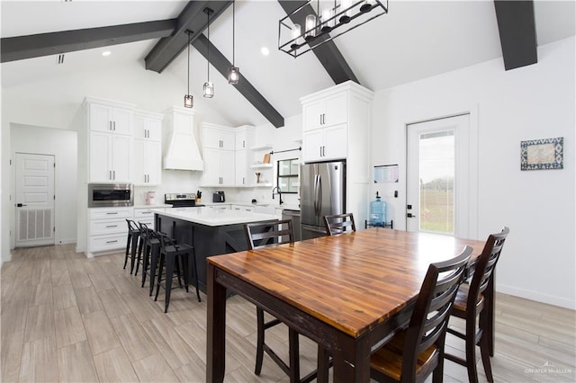 dining room with beamed ceiling, light wood-type flooring, visible vents, and baseboards