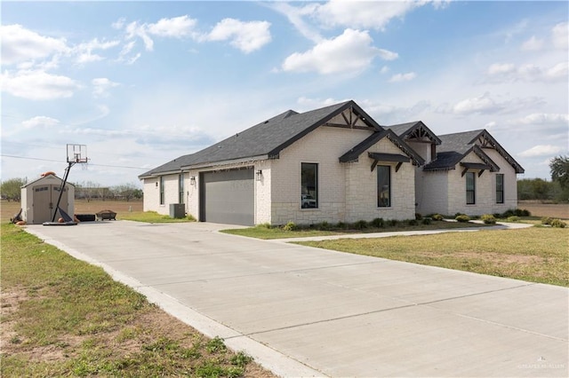 view of front of house featuring a garage, a storage shed, driveway, an outdoor structure, and a front lawn