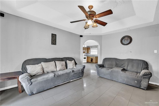 1101 Boston St, Edinburg, TX 78541 - tiled living area featuring baseboards, arched walkways, a ceiling fan, and a raised ceiling