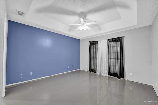 1101 Boston St, Edinburg, TX 78541 - unfurnished room with a tray ceiling, visible vents, a ceiling fan, baseboards, and a textured ceiling