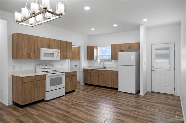 kitchen with white appliances, sink, decorative light fixtures, an inviting chandelier, and dark hardwood / wood-style floors