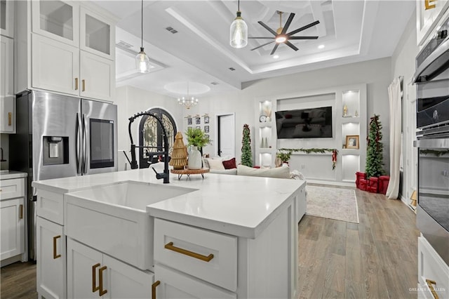 kitchen featuring stainless steel fridge, a tray ceiling, sink, white cabinetry, and hanging light fixtures