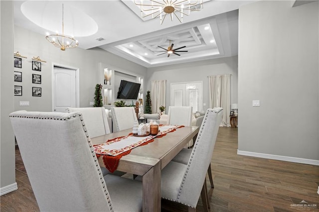 dining space featuring dark hardwood / wood-style floors, a raised ceiling, and ceiling fan with notable chandelier