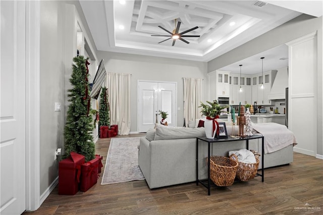 living room with dark hardwood / wood-style floors, ceiling fan, a high ceiling, and coffered ceiling