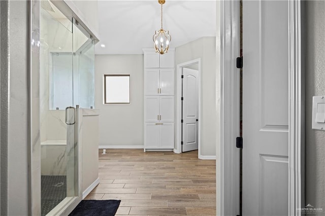 bathroom with hardwood / wood-style flooring, an inviting chandelier, and a shower with door