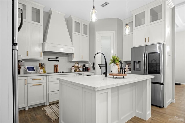 kitchen featuring premium range hood, stainless steel fridge, and white cabinets