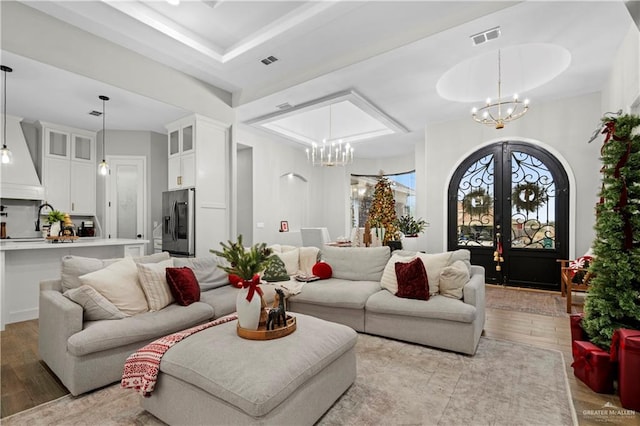 living room with french doors, light hardwood / wood-style floors, and a notable chandelier