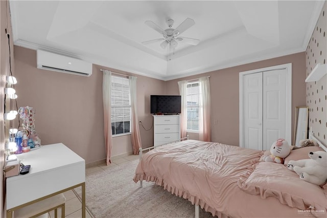 bedroom featuring a wall unit AC, light tile patterned flooring, a closet, crown molding, and a raised ceiling