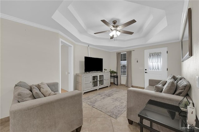 living area featuring a tray ceiling, light tile patterned floors, crown molding, and ceiling fan