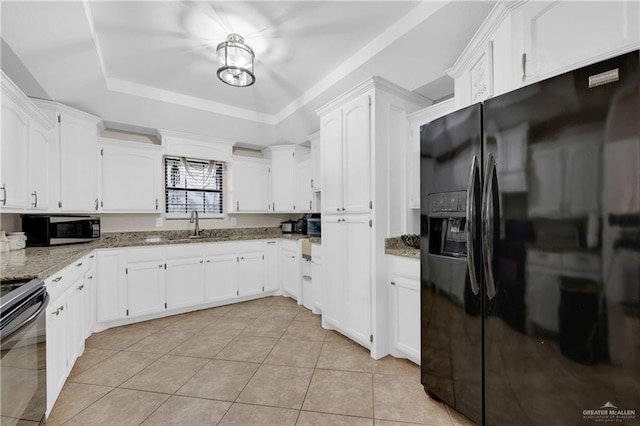 kitchen with light stone counters, white cabinetry, black appliances, and a raised ceiling