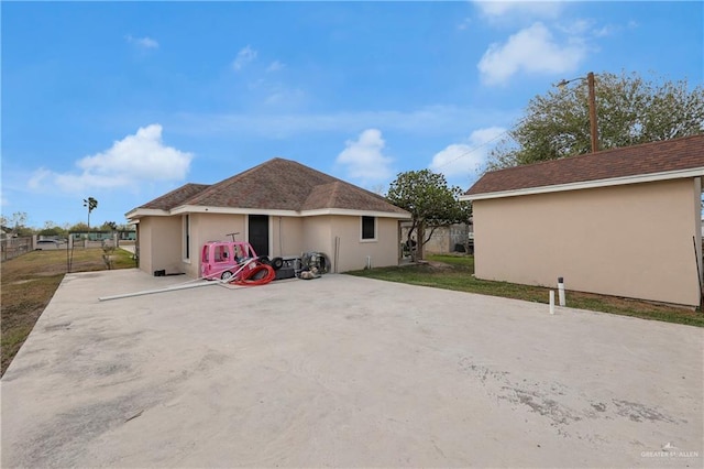 back of house with stucco siding, a lawn, and fence