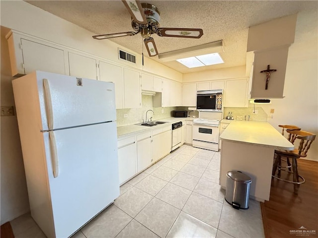 800 E Dallas Ave Unit 17, Mcallen, TX 78501 - kitchen with white appliances, a peninsula, light countertops, a skylight, and a textured ceiling