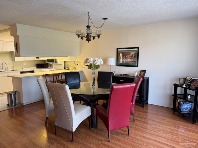 800 E Dallas Ave Unit 17, Mcallen, TX 78501 - dining room with a chandelier, light wood-style flooring, and a textured ceiling