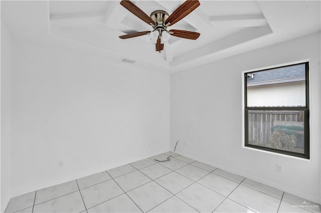 empty room featuring ceiling fan, light tile patterned floors, and a raised ceiling