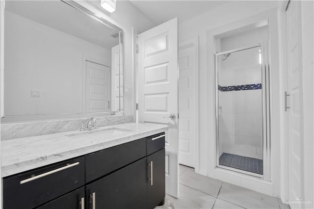 bathroom featuring tile patterned flooring, vanity, and walk in shower