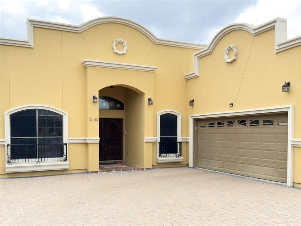 view of front of house featuring a garage, decorative driveway, and stucco siding