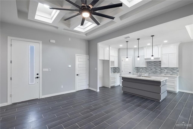 kitchen with pendant lighting, a center island with sink, sink, dark hardwood / wood-style floors, and white cabinetry