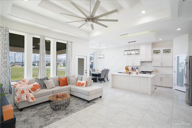 living room with a tray ceiling and ceiling fan