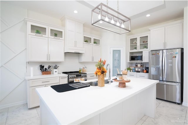 kitchen featuring white cabinetry, sink, decorative light fixtures, a kitchen island with sink, and appliances with stainless steel finishes