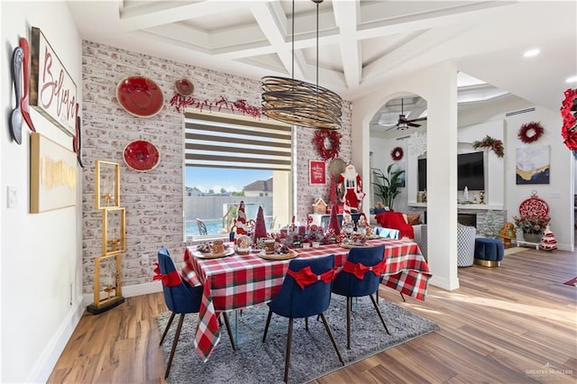 dining space with ceiling fan with notable chandelier, beam ceiling, wood-type flooring, and coffered ceiling