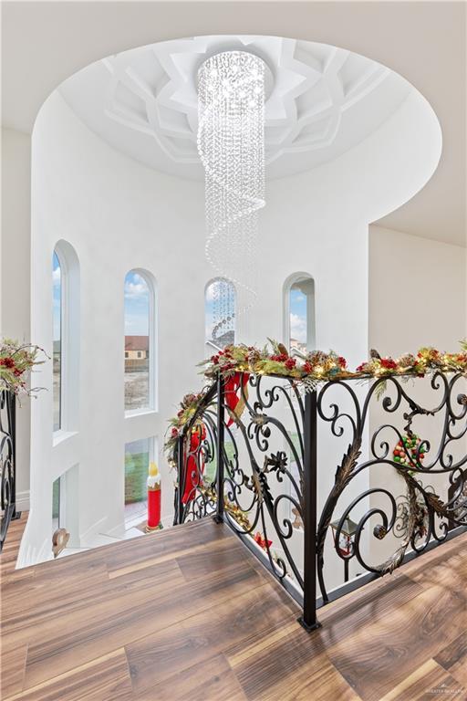 interior space featuring coffered ceiling, a towering ceiling, hardwood / wood-style floors, and an inviting chandelier