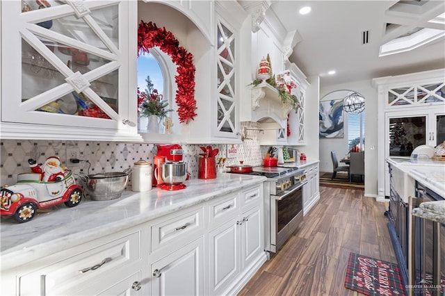 kitchen with high end stove, light stone counters, tasteful backsplash, and white cabinets