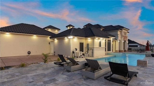 back house at dusk featuring a patio area