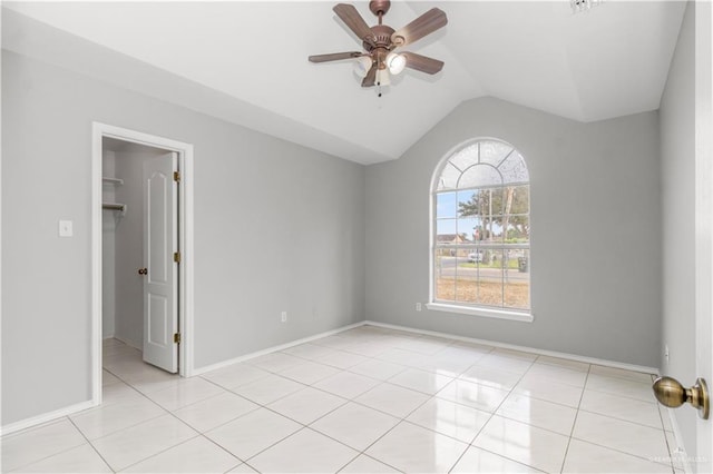 empty room featuring ceiling fan, light tile patterned floors, and vaulted ceiling