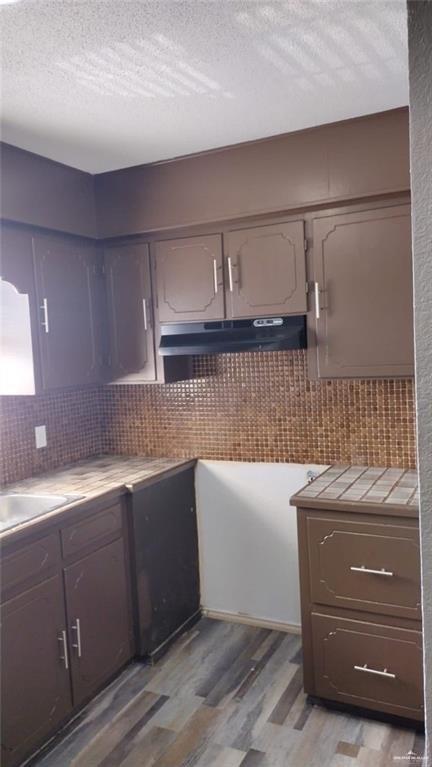 kitchen featuring tile countertops, a textured ceiling, backsplash, and hardwood / wood-style flooring