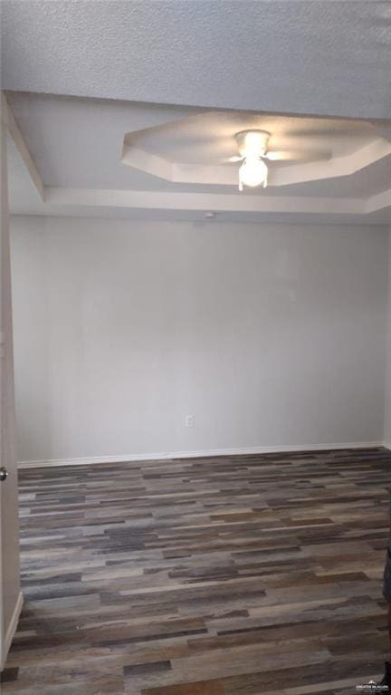 empty room featuring dark hardwood / wood-style flooring and a raised ceiling