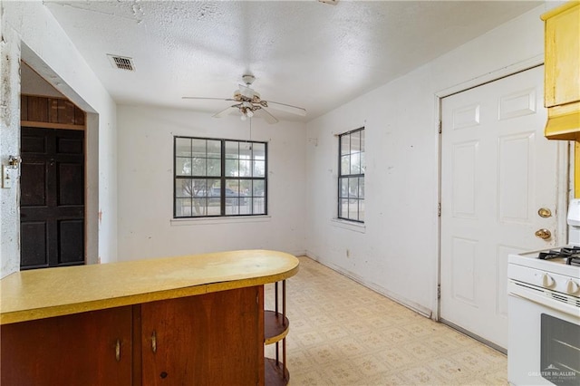 kitchen with a textured ceiling, white range with gas cooktop, and ceiling fan