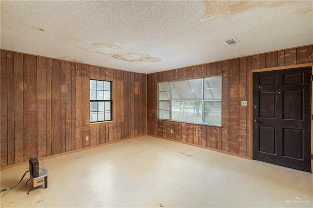 spare room featuring a textured ceiling and wood walls