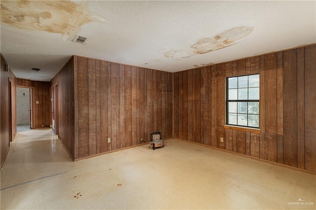 unfurnished room featuring a textured ceiling and wood walls