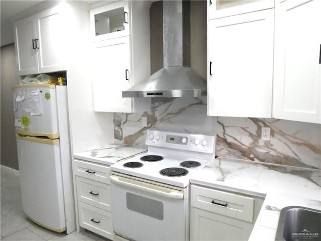 kitchen with white appliances, light stone countertops, white cabinets, decorative backsplash, and wall chimney exhaust hood