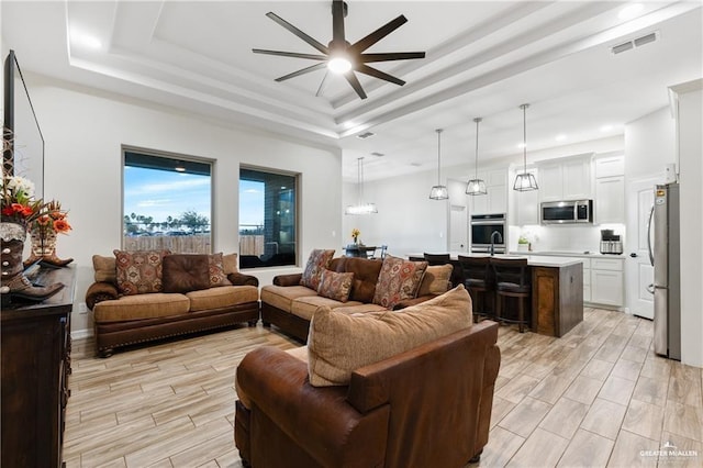 living room featuring a raised ceiling and ceiling fan