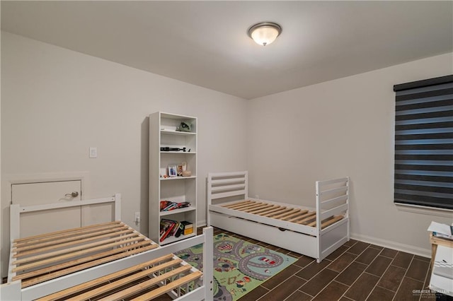 bedroom featuring baseboards and wood tiled floor