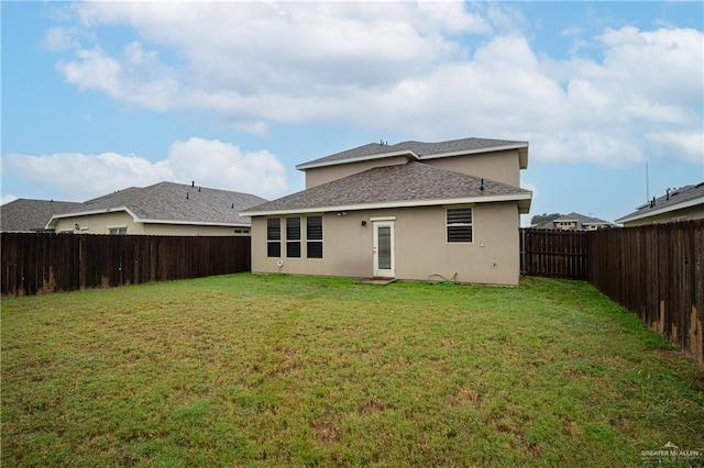 back of house featuring stucco siding, a fenced backyard, and a yard