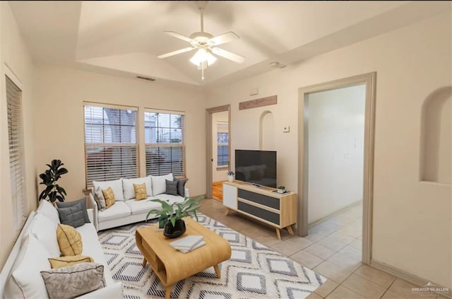 living room with ceiling fan, light tile patterned flooring, and a tray ceiling