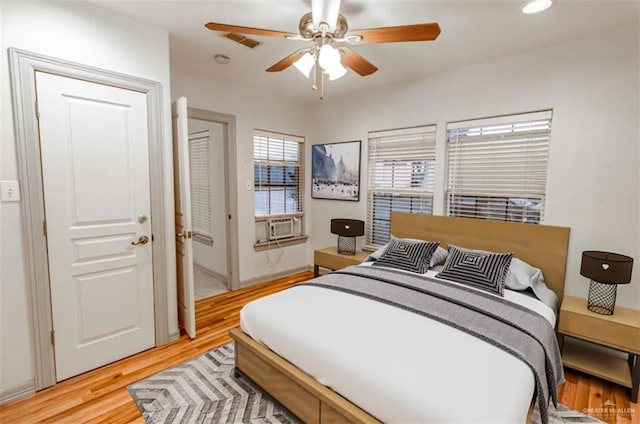 bedroom featuring ceiling fan, cooling unit, and light hardwood / wood-style floors