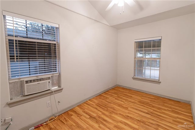 empty room with light wood-type flooring, ceiling fan, lofted ceiling, and cooling unit