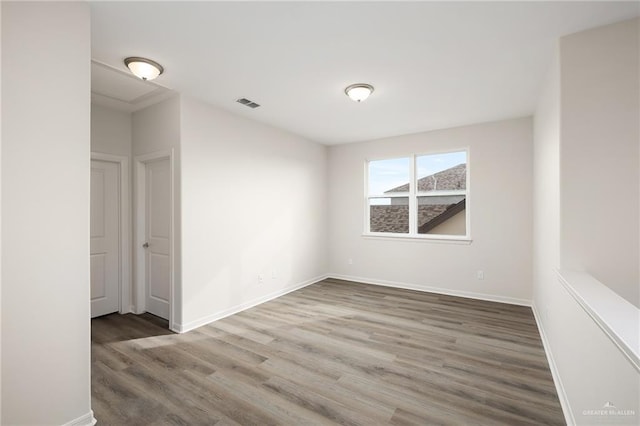 unfurnished room featuring visible vents, baseboards, and wood finished floors