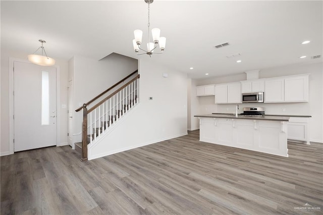 kitchen with dark countertops, a sink, stainless steel appliances, recessed lighting, and light wood-type flooring