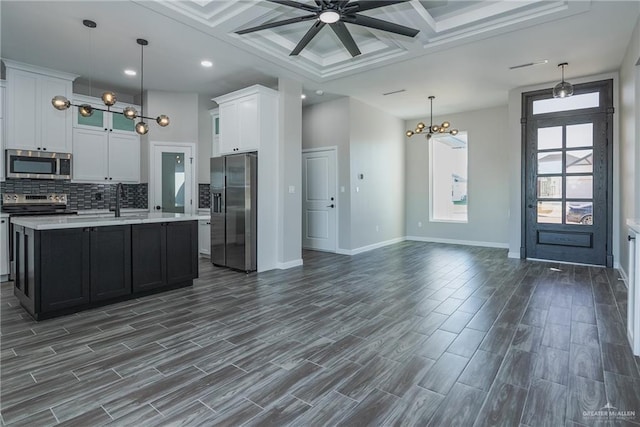 kitchen with stainless steel appliances, open floor plan, hanging light fixtures, light countertops, and a center island with sink