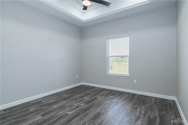 unfurnished room featuring a ceiling fan, dark wood-style flooring, a raised ceiling, and baseboards